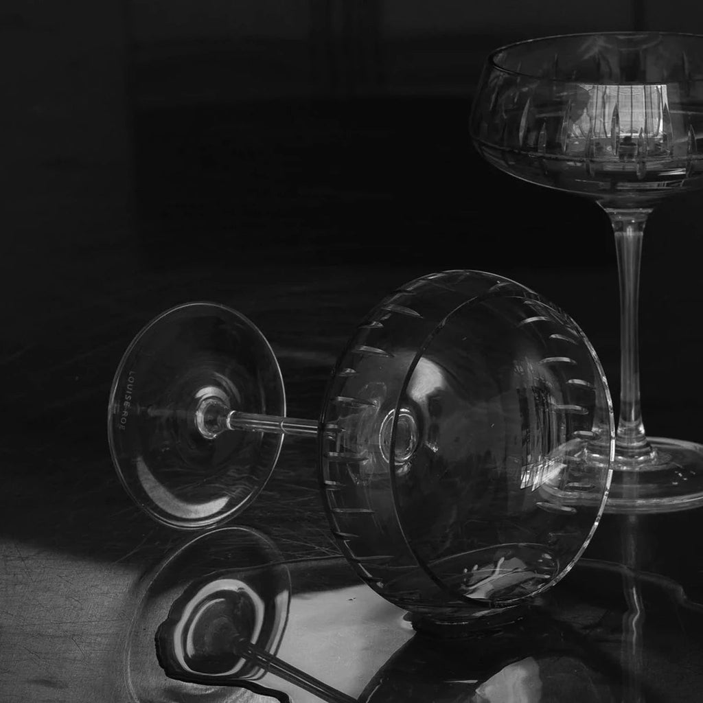 A black and white photo of two Louise Roe Crystal Champagne Coupes on a table at Gestalt Haus.