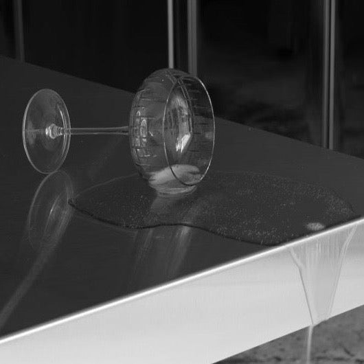 A black and white photo of a Louise Roe crystal champagne coupe on a table at Gestalt Haus.