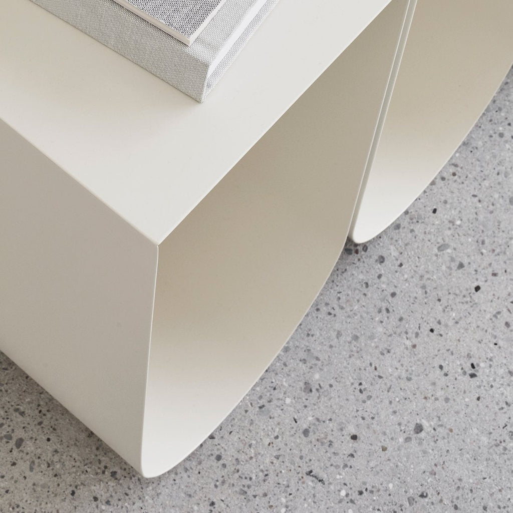 A white CURVED SIDE TABLE from KRISTINA DAM STUDIO with a book on it at Gestalt Haus.