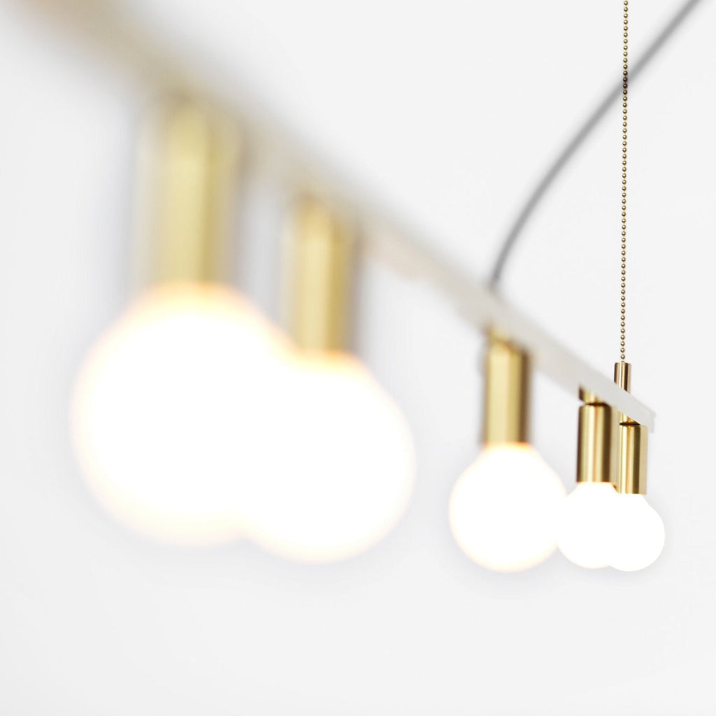 Four DOT LINE SUSPENSION light bulbs hanging from a gold chain, inspired by the Gestalt Haus philosophy, by LAMBERT ET FILS.
