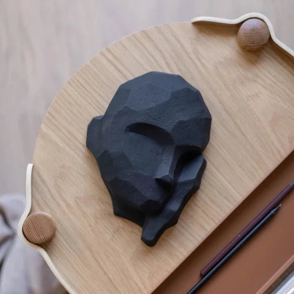 A black DREAMER SCULPTURE of a face on a COOEE Gestalt wooden table.