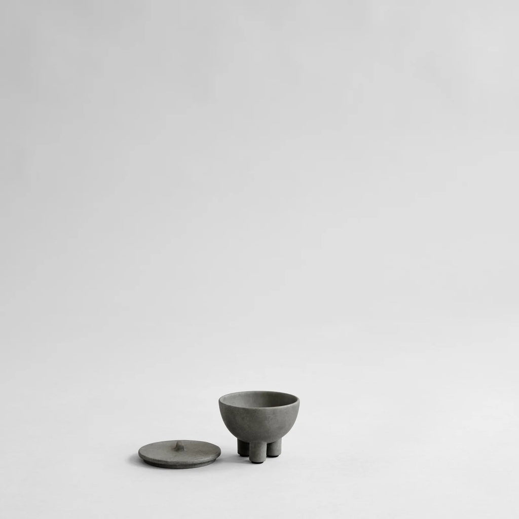 A small grey DUCK JAR - MINI by 101 COPENHAGEN sitting on a white surface with Gestalt Haus design.
