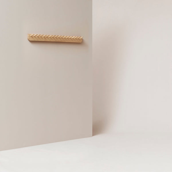 An ECHO COAT RACK 88 by FORM & REFINE hanging on a white wall in a Gestalt Haus-inspired room.