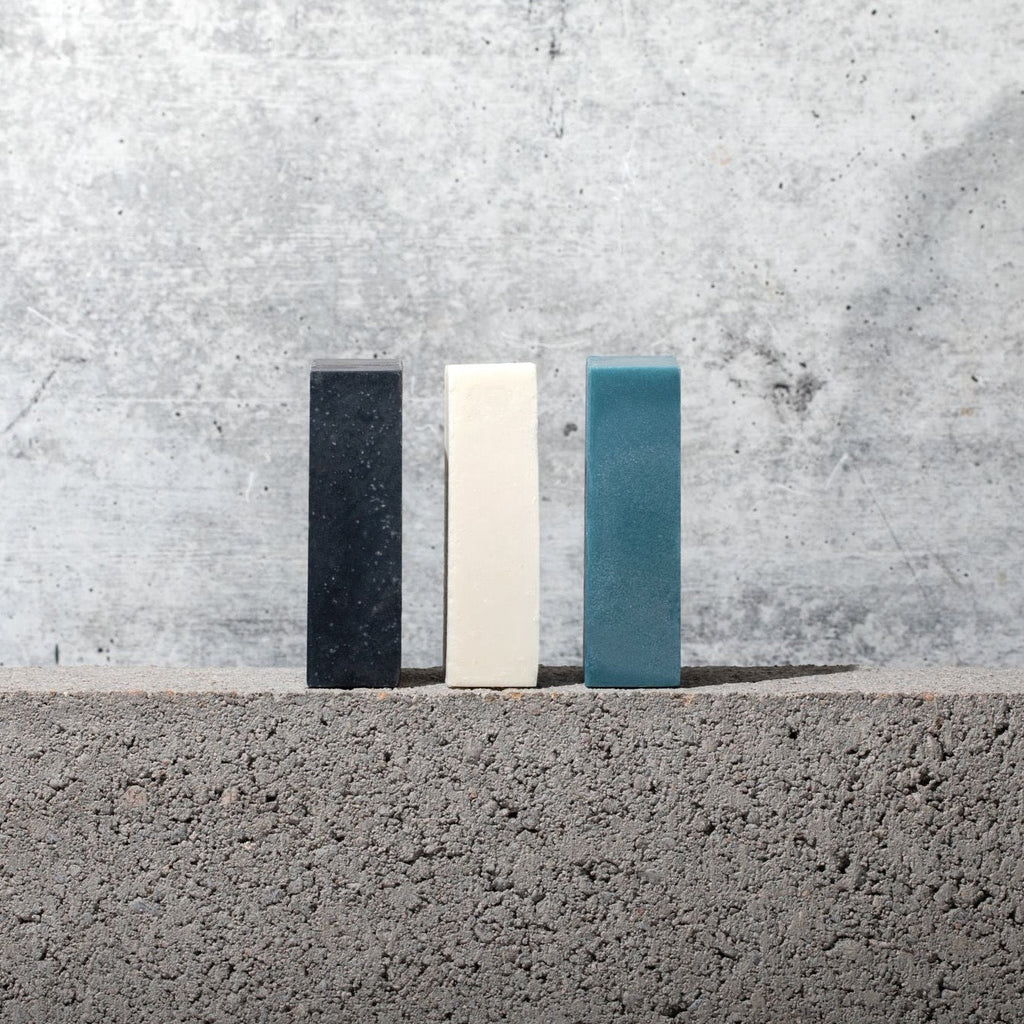 Three Gestalt Haus Bar Soaps sitting on top of a concrete wall.