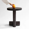 A hand reaching for an ÉVORA SIDE TABLE by ORIGIN MADE on a black Gestalt Haus table.