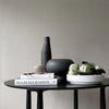 A black FORMALISM BOWL with a book and a vase by 101 COPENHAGEN that embodies the essence of Gestalt Haus.