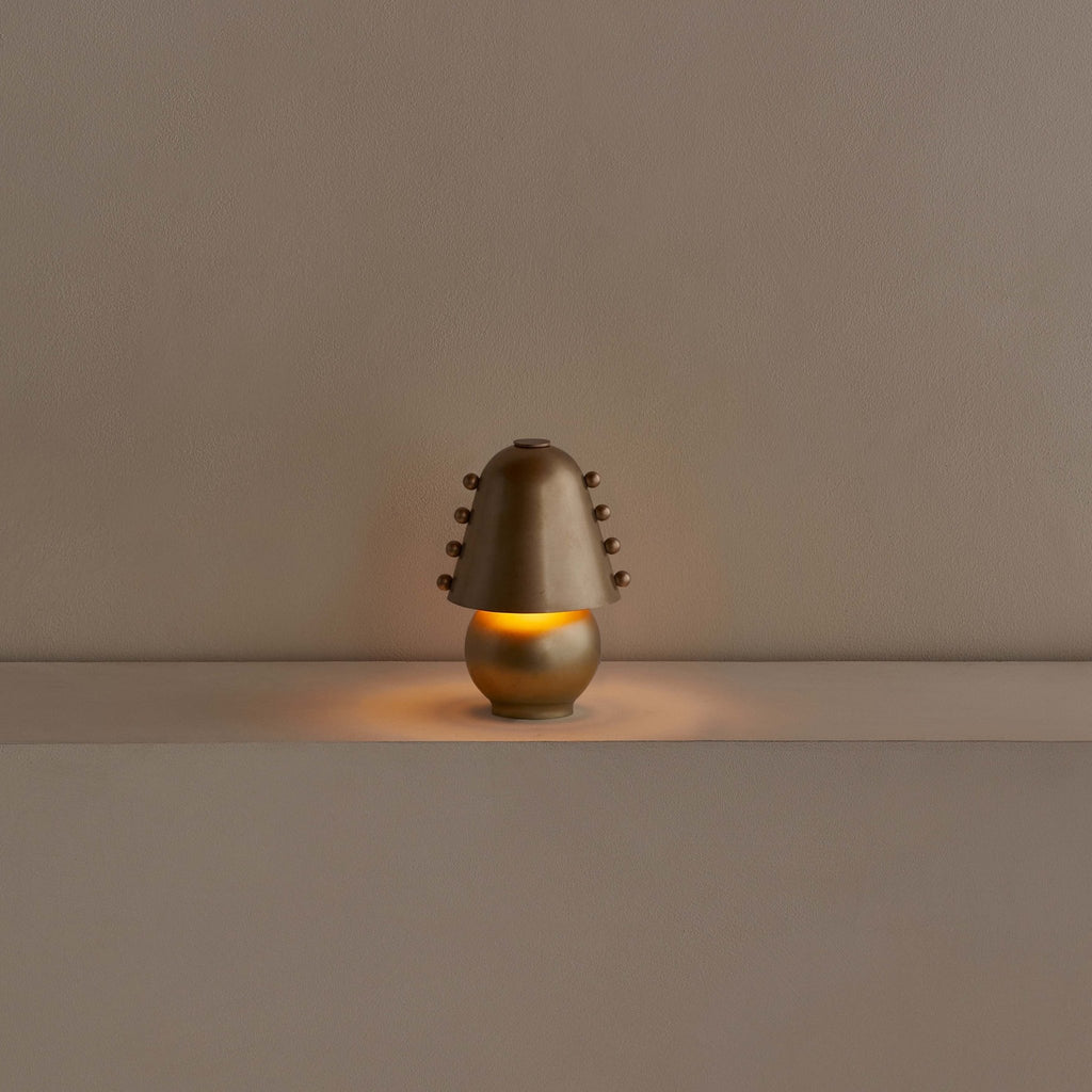 A small Gestalt Haus table lamp on a table in front of a white wall.
