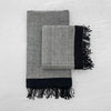 A HAND WOVEN TOWEL COLLECTION by SERA HELSINKI featuring grey and black designs on a white surface.
