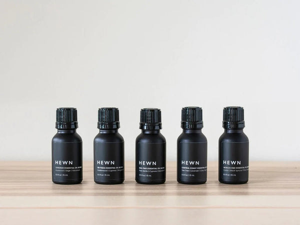 Five bottles of HEWN essential oils on a wooden table at Gestalt Haus.