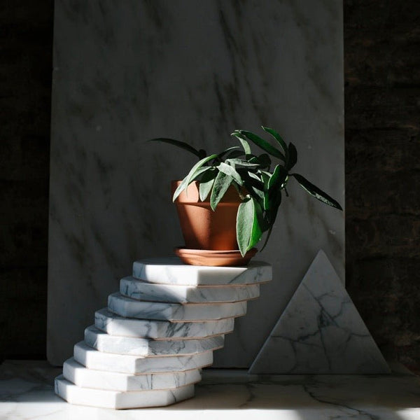 A HEXAGON MARBLE TRIVET from Gestalt Haus sits on top of a stack of marbles.