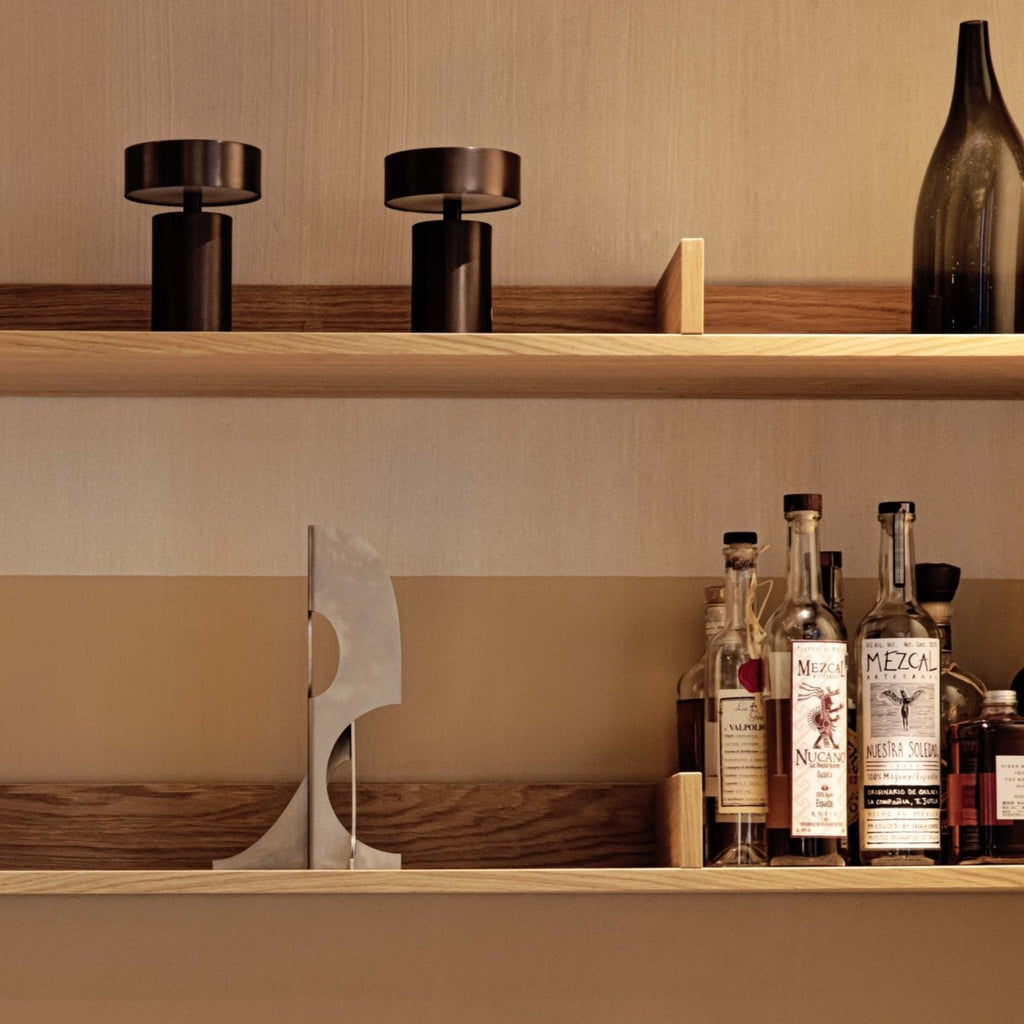 An IN-BETWEEN ELEMENTS wooden shelf with several bottles on it by ATELIER PLATEAU.