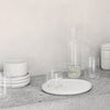 A set of white plates and Kristina Dam Studio capsule glasses on a concrete counter at Gestalt Haus.