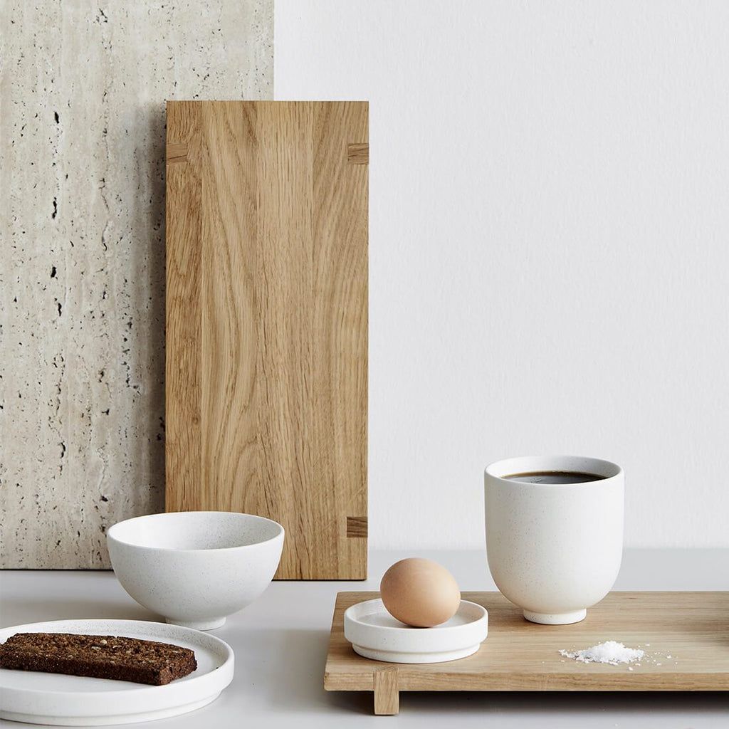 A Japanese wood board tray with a cup of coffee and a slice of bread by Kristina Dam Studio in Gestalt style.