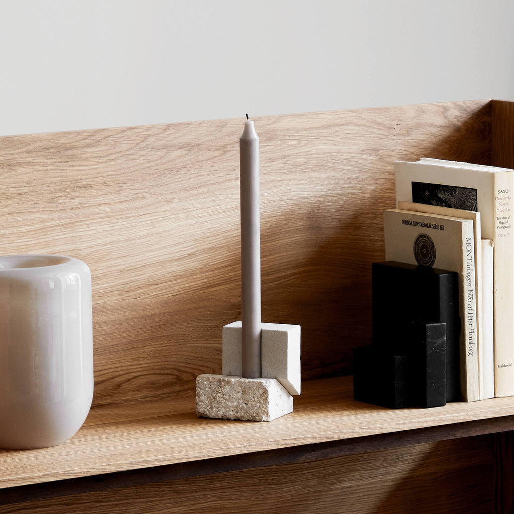 A Gestalt Haus featuring an OFFSET CANDLE HOLDER VOL. 2 by KRISTINA DAM STUDIO and a vase on a shelf with books.