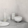 A table featuring a SETOMONO BOWL SET LARGE and a bottle by KRISTINA DAM STUDIO.