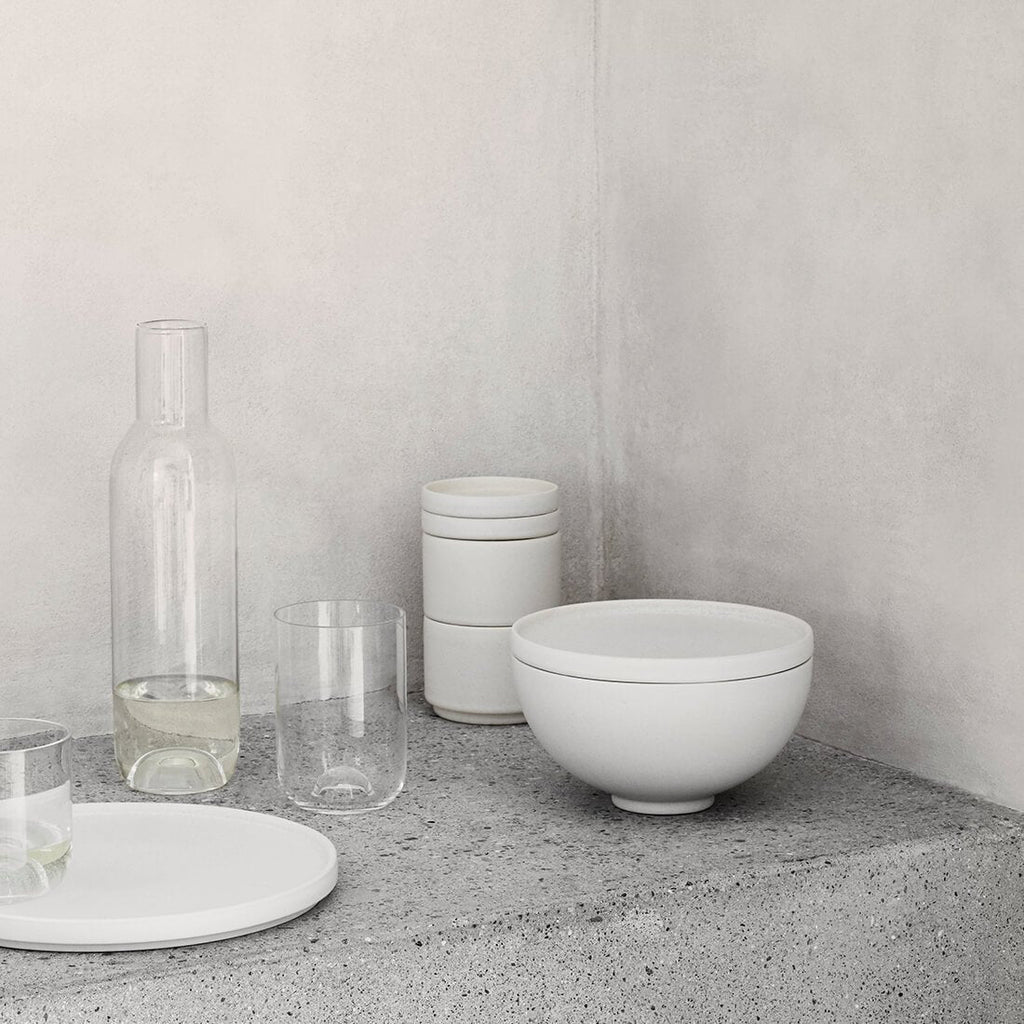 A table featuring a SETOMONO BOWL SET LARGE and a bottle by KRISTINA DAM STUDIO.
