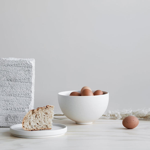 A Gestalt Haus SETOMONO BOWL SET LARGE by KRISTINA DAM STUDIO with eggs and bread on a table next to a block of wood.