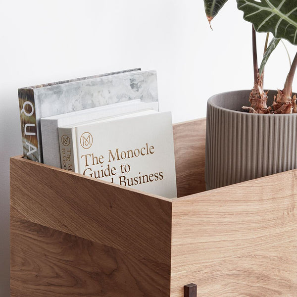 A Kristina Dam Studio STACK STORAGE BOX featuring a book and a plant, creating a harmonious Gestalt Haus.