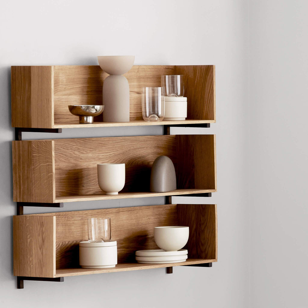 A STACK WALL SHELF by KRISTINA DAM STUDIO displaying dishes and glasses.