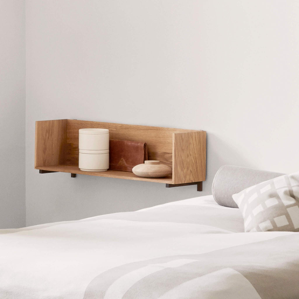A white bed with a Kristina Dam Studio STACK WALL SHELF displaying a Gestalt Haus artwork on the wall.
