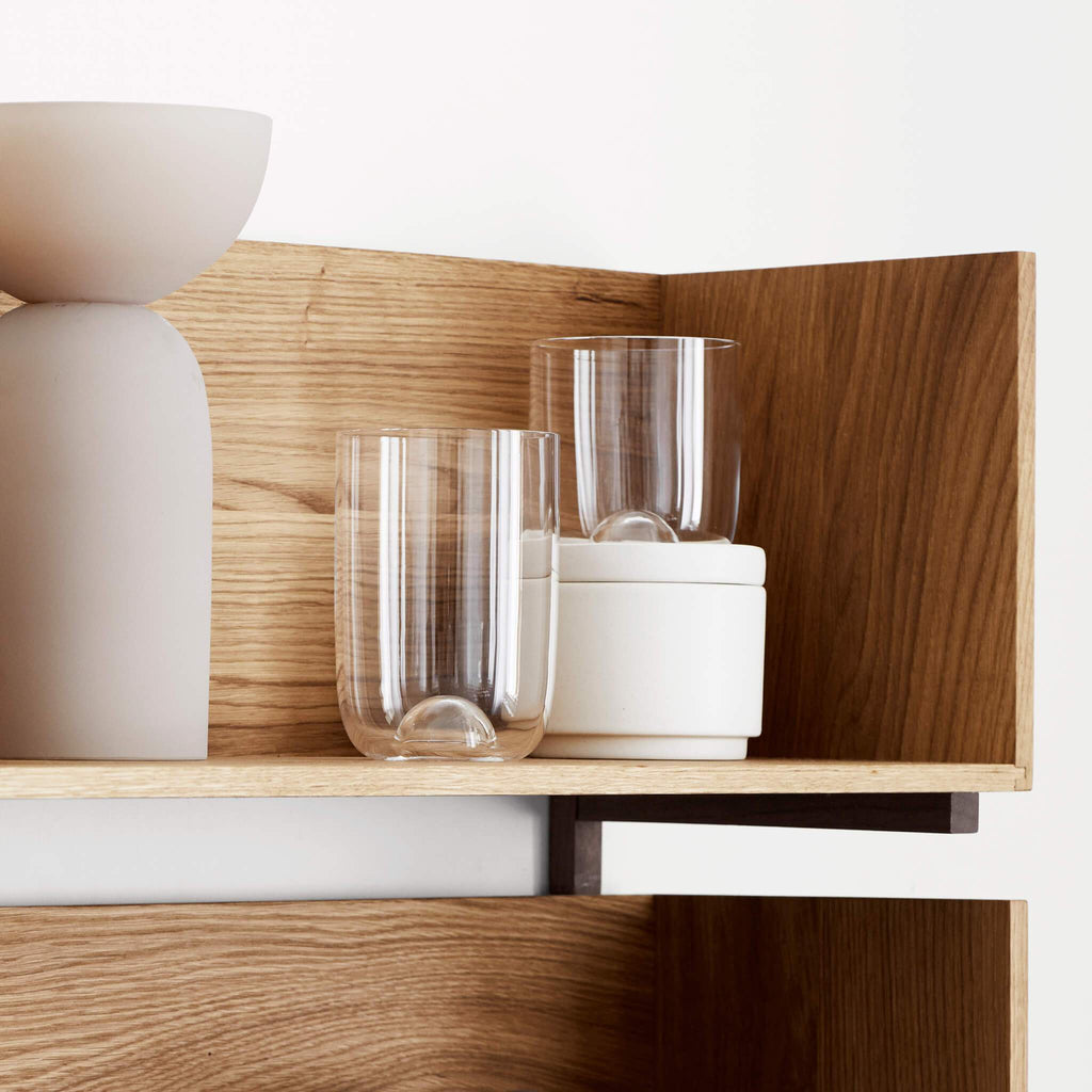 A Gestalt Haus stack wall shelf from Kristina Dam Studio displaying two glasses and a vase.