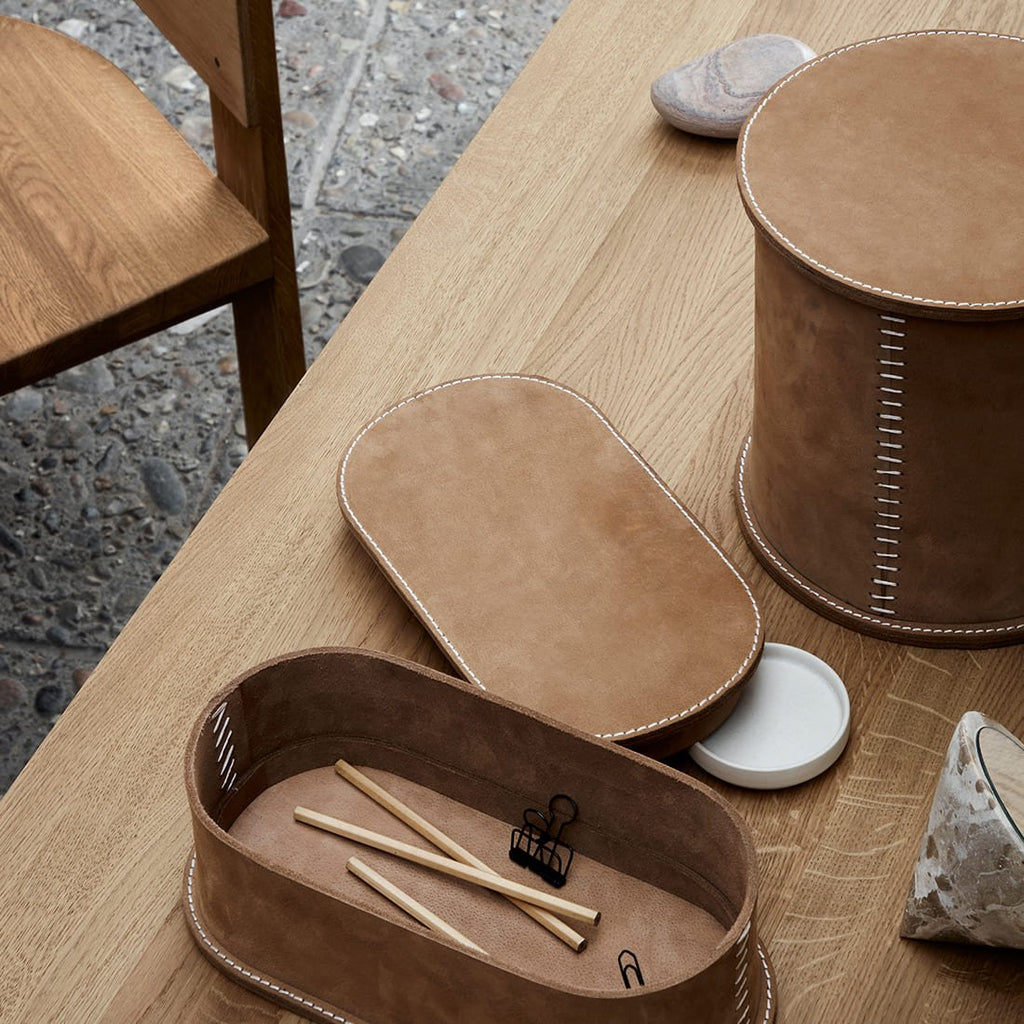 A wooden table with a STITCHED LEATHER BOX from KRISTINA DAM STUDIO and a pair of chopsticks at Gestalt Haus.