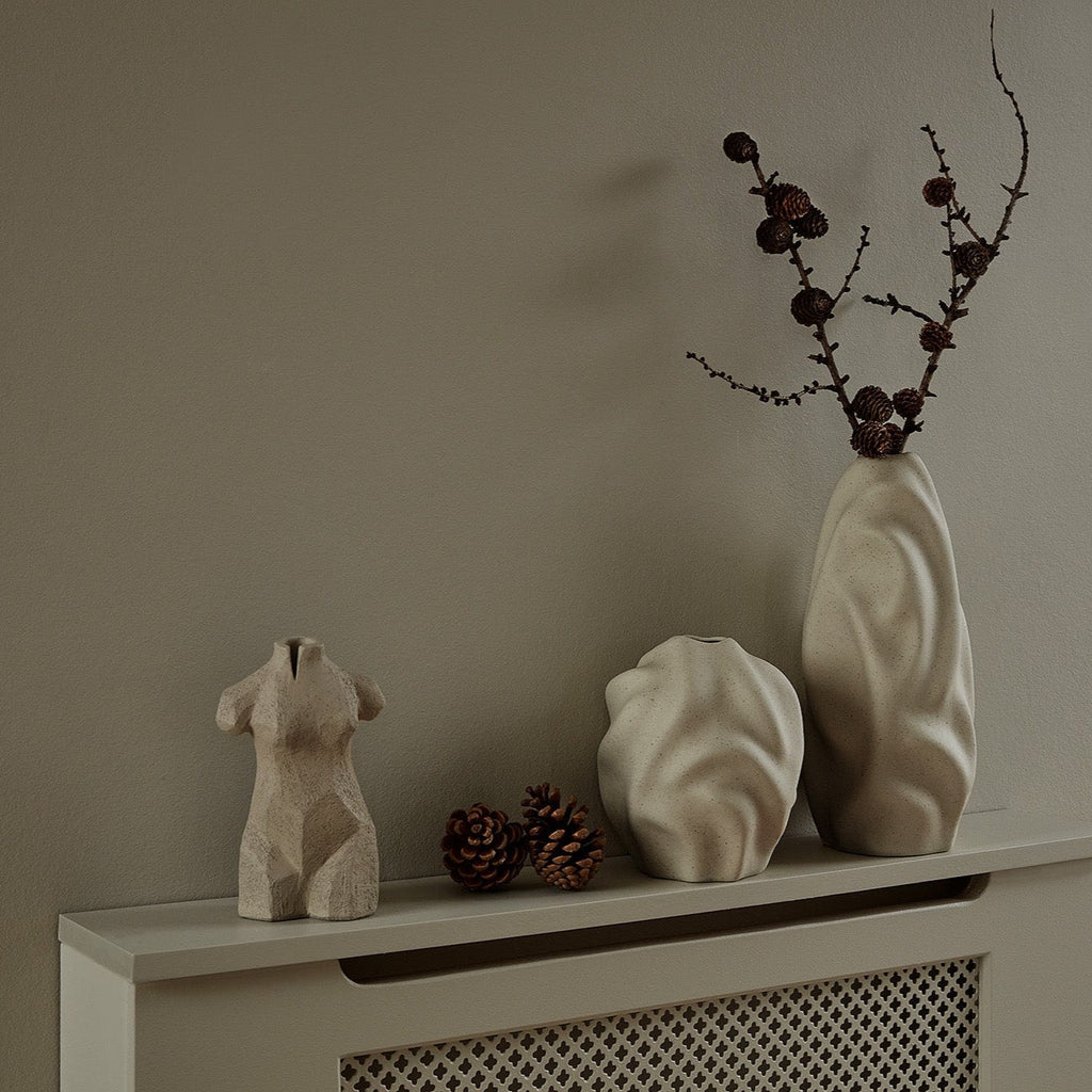 A COOEE mantle adorned with three LEAH SCULPTURE vases on it.