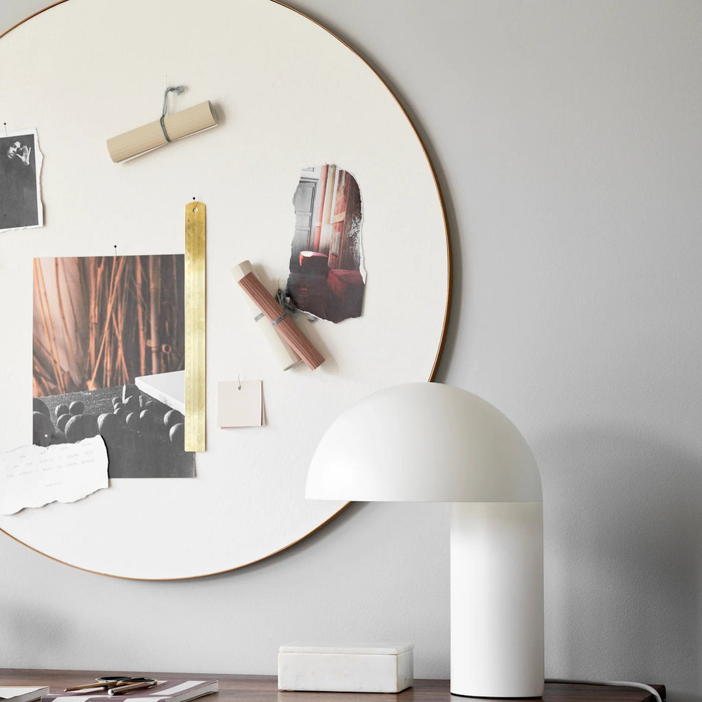 A white wall with a round mirror and a GEJST LEERY TABLE LAMP, creating a Gestalt Haus aesthetic.