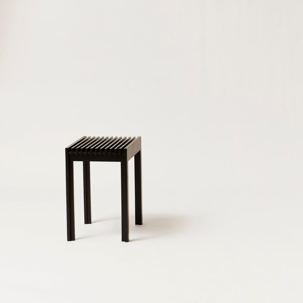 A small black FORM & REFINE stool on a white background in the Gestalt Haus style.