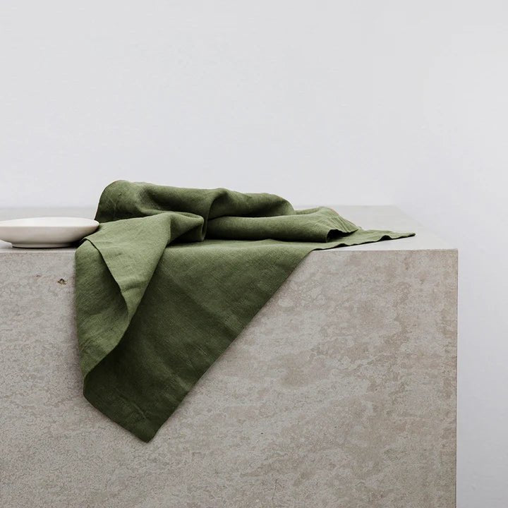 A green LINEN NAPKIN, CULTIVER, sitting on top of a concrete surface at Gestalt Haus.