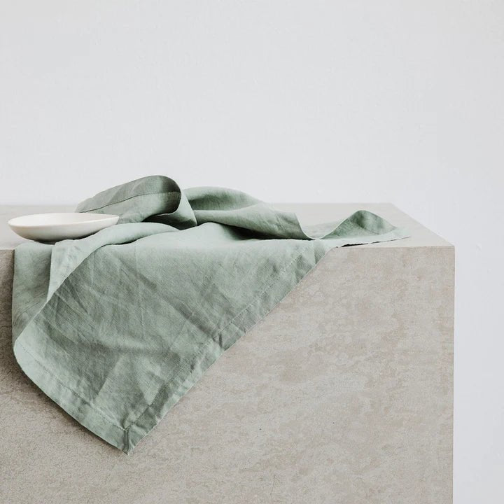 A green CULTIVER linen napkin atop a Gestalt Haus concrete table.