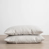 Two LINEN PILLOWCASES stacked on top of each other on a wooden table. (Brand: CULTIVER)