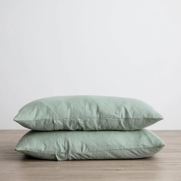 Two green CULTIVER LINEN PILLOWCASES on top of a wooden table.