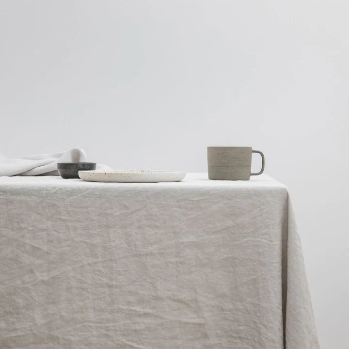 A LINEN TABLECLOTH from CULTIVER adorned with a cup and plate creates a warm and inviting atmosphere at Gestalt Haus.