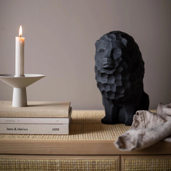 A black LION OF JUDAH SCULPTURE made by COOEE sits on a shelf next to books at Gestalt Haus.
