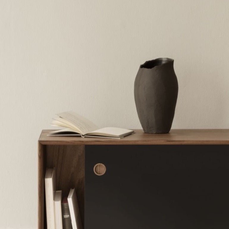 A black sideboard with books and a SIBAST MAGNOLIA VASE in a Gestalt Haus setting.