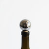 A bottle of MASS WINE STOPPERS with a ball on it, manufactured by FS OBJECTS, inspired by Gestalt Haus.