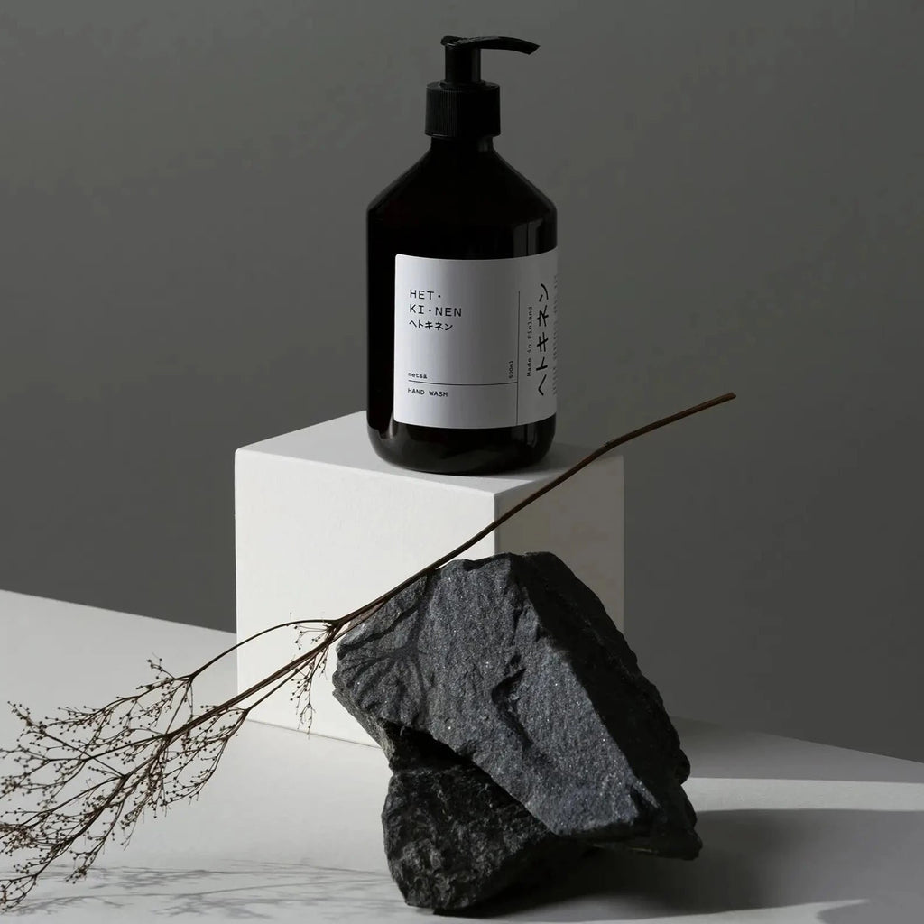 A bottle of METSÄ HAND SOAP next to a rock.