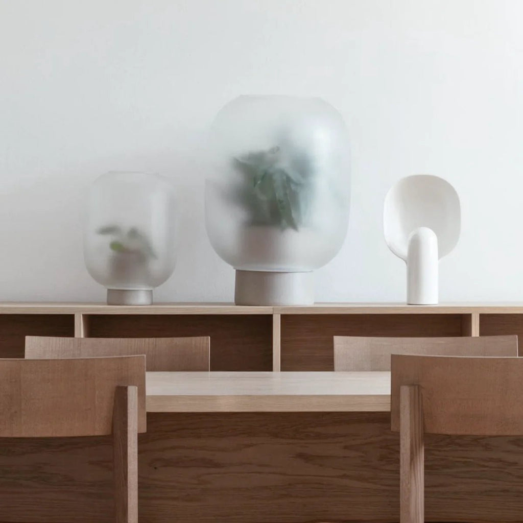 A dining room with a table, chairs, and NEBL FLOWERPOT vases from Gestalt Haus.
