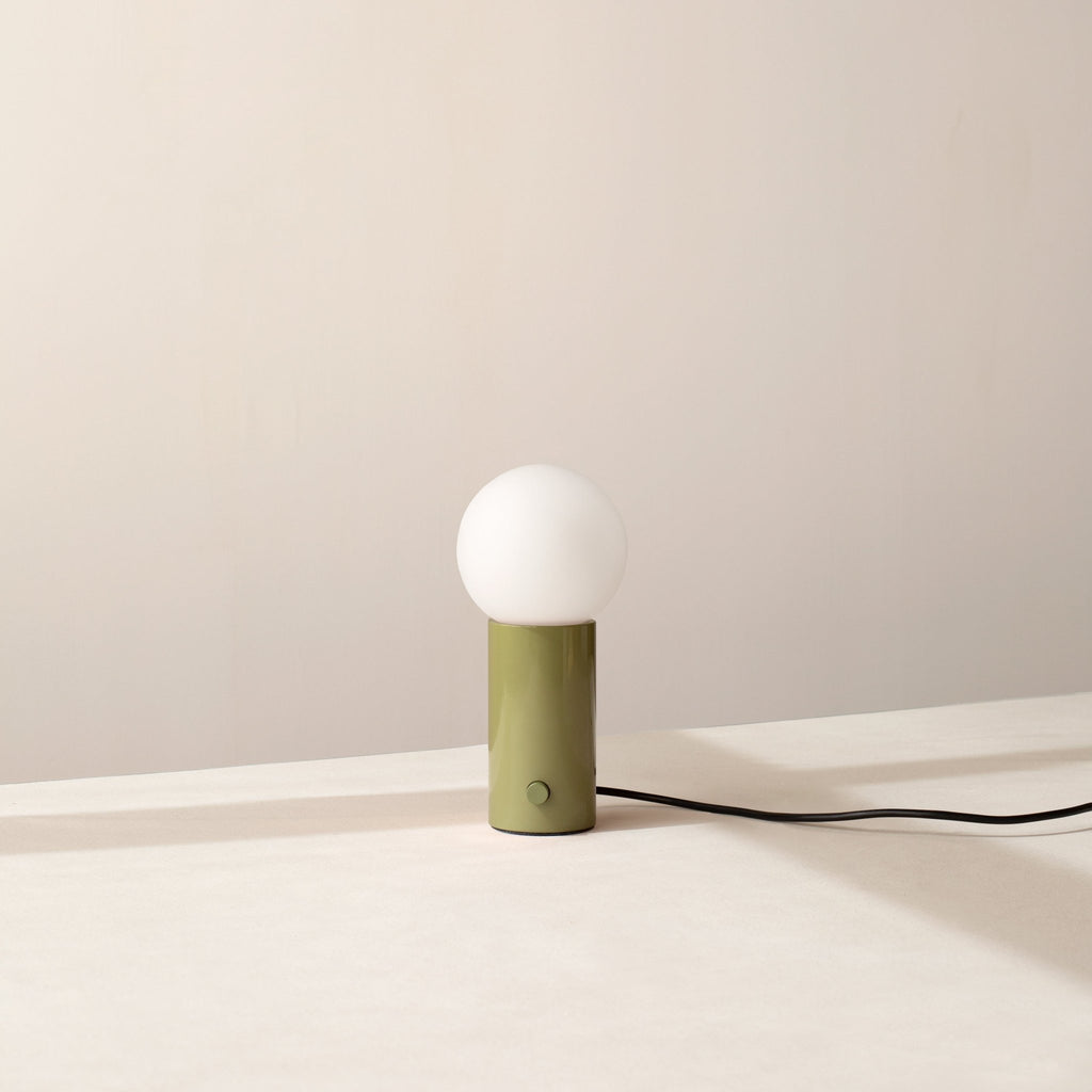 An ORB TABLE LAMP from Gestalt Haus with a green shade and a white cord.