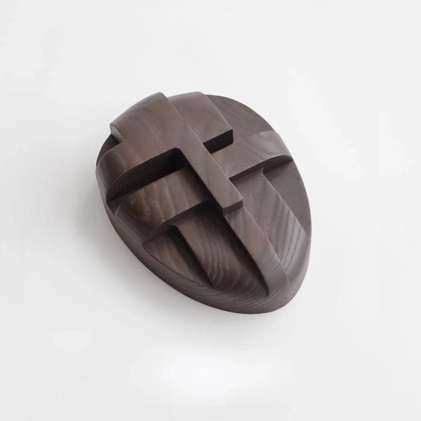 An ORNAMENT AND CRIME wooden cross on a white surface, made by ORIGIN MADE in Gestalt Haus style.
