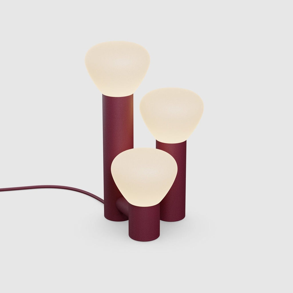 A Gestalt Haus PARC 06 TABLE LAMP by LAMBERT ET FILS with three burgundy lamps on it.
