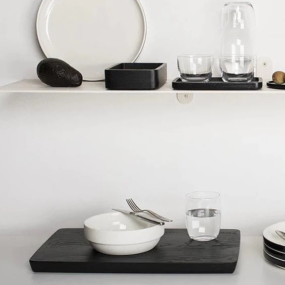 A black and white shelf displaying Gestalt Haus plates and bowls by SERAX.