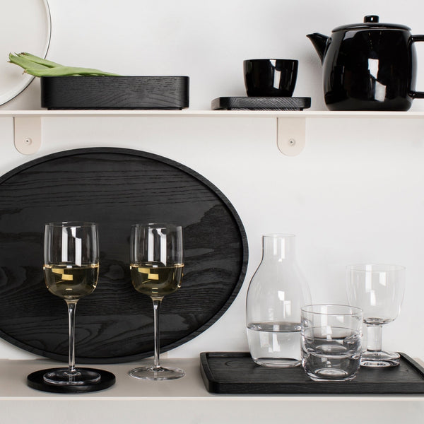 A shelf with PASSE-PARTOUT glassware by Vincent Van Duysen, including wine glasses and a teapot from the brand SERAX, displayed in the Gestalt Haus.