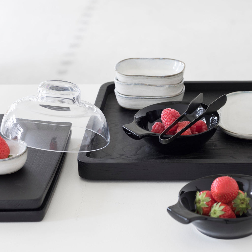 A black PASSE-PARTOUT tray by Vincent Van Duysen with strawberries and bowls on it, from the brand SERAX, showcasing the unique aesthetic of Gestalt Haus.