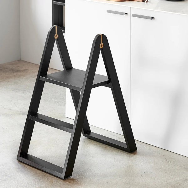 A black REECH STEPLADDER by GEJST in front of a white kitchen at Gestalt Haus.