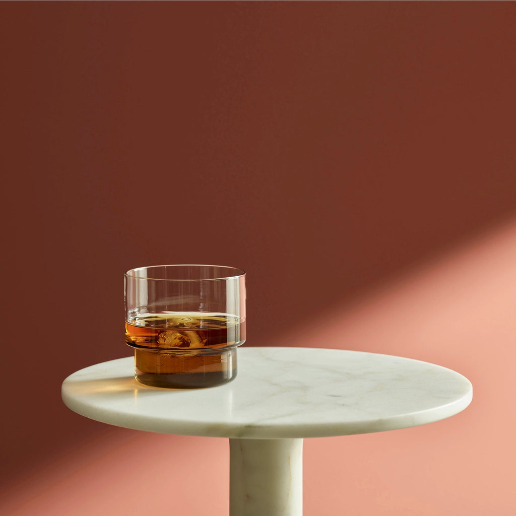 A glass of Rye whiskey sits on a marble table from Aaron Probyn at Gestalt Haus.