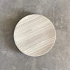 A round white SABI BOWL plate on a concrete surface by BRANDT COLLECTIVE at Gestalt Haus.