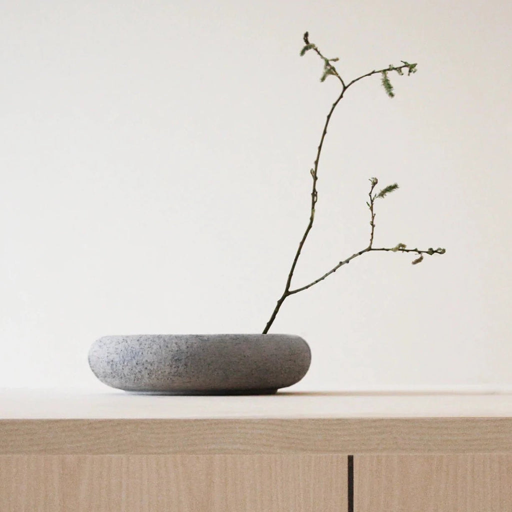 An ORIGIN MADE Gestalt Haus VASE with a branch sitting on top of a table.