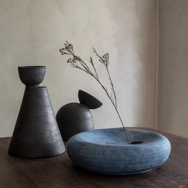 An Origin Made salt vase with a flower in it sits on a wooden table at Gestalt Haus.